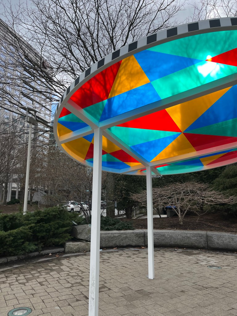 A large stained glass sun dial on a city sidewalk